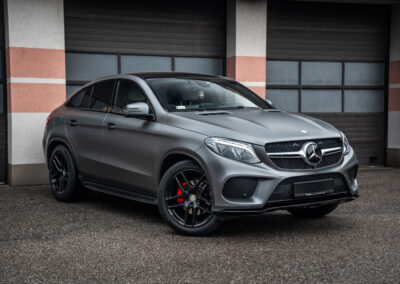 Szary Mercedes SUV w ujęciu z profilu przy garażu