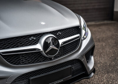 Przód srebrnego Mercedesa z wyeksponowanym logo marki